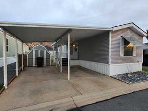 View of parking featuring a storage unit, a carport, and driveway