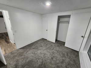 Unfurnished bedroom with a textured ceiling, carpet, and a closet