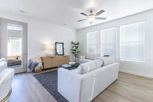 Living room featuring light wood-style floors, a ceiling fan, and healthy amount of natural light