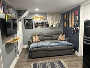 Bedroom featuring wood finished floors, freestanding refrigerator, ornamental molding, and recessed lighting