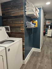 Laundry area featuring wooden walls, dark wood-style flooring, recessed lighting, and washing machine and dryer
