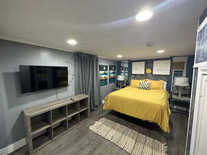 Bedroom with wood finished floors, recessed lighting, and ornamental molding