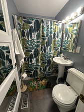 Full bath featuring a shower with curtain and dark tile patterned flooring