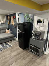 Kitchen with freestanding refrigerator, crown molding, light wood-type flooring, and stainless steel microwave