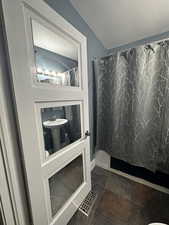 Full bathroom with shower / bath combo with shower curtain and dark tile patterned floors