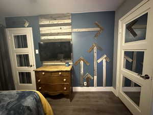 Bedroom with dark wood finished floors and baseboards