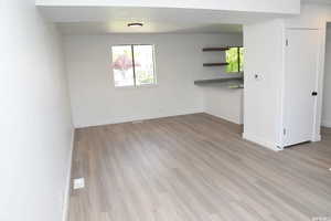 Unfurnished living room featuring baseboards and light wood-type flooring