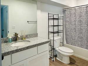 Bathroom featuring light wood-type flooring, vanity, shower / tub combo, and a textured ceiling