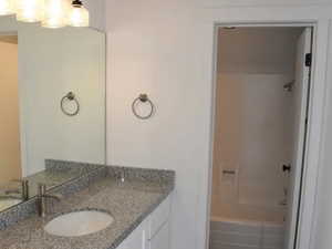 Bathroom with vanity, dark wood-type flooring, and shower / bath combination