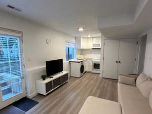 Living area featuring a textured ceiling, washer / dryer, and light wood-style floors