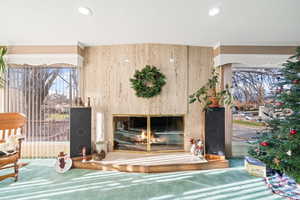 Interior space featuring healthy amount of natural light, a glass covered fireplace, crown molding, and carpet flooring