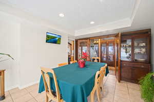 Dining space featuring french doors, light tile patterned floors, crown molding, a textured ceiling, and recessed lighting