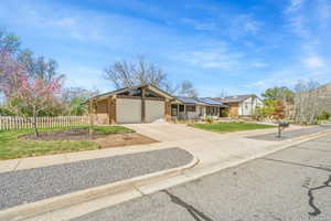 View of front of property featuring an attached garage, driveway, and roof mounted solar panels