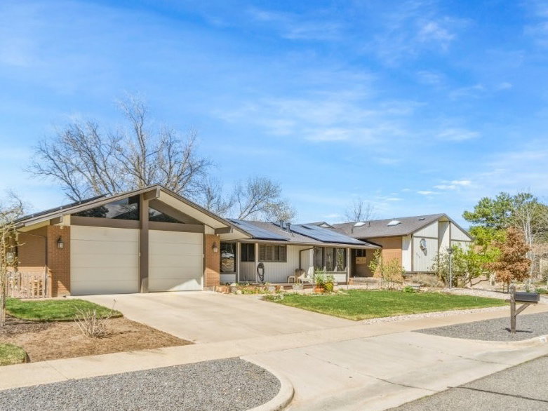 View of front of property featuring an attached garage, driveway, and roof mounted solar panels