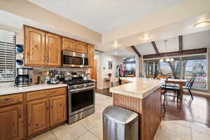 Kitchen with brown cabinets, appliances with stainless steel finishes, tasteful backsplash, pendant lighting, and a textured ceiling