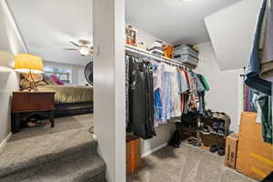 Walk in closet featuring light carpet and a ceiling fan