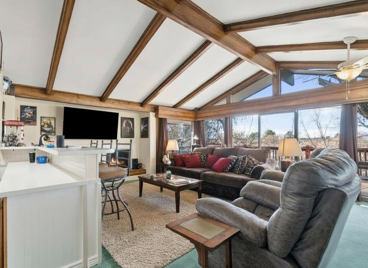 Living area featuring a vaulted ceiling with exposed wood beams, a built-in fireplace, and expansive windows