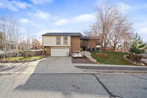 View of front of property featuring driveway, a front lawn, an attached garage, and brick siding