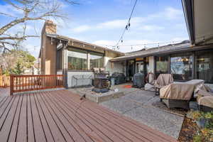 Wooden terrace featuring grilling area, an outdoor fire pit, and a patio area