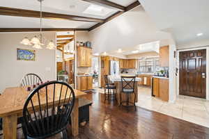 Dining space featuring light wood-style floors, a skylight, a chandelier, and high vaulted ceiling