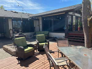 Wooden deck featuring outdoor lounge area, a sunroom, and a patio