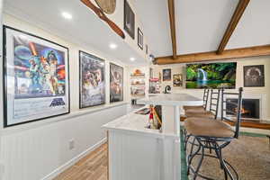 Indoor wet bar with a fireplace, wood finish floors, beamed ceiling, recessed lighting, and white cabinetry
