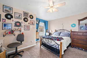 Carpeted bedroom with ceiling fan and baseboards