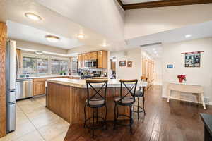 Kitchen with light countertops, a kitchen bar, stainless steel appliances, recessed lighting, and light wood-type flooring
