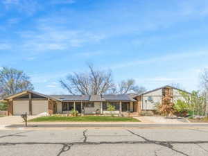 Mid-century home featuring solar panels, a garage, and concrete driveway