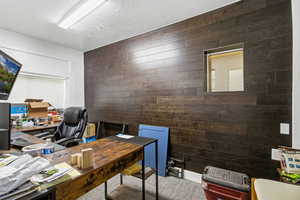 Office space with wood walls and a textured ceiling