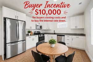 Modern kitchen featuring white shaker cabinetry, stainless steel appliances, dark countertops, and wood-finish flooring