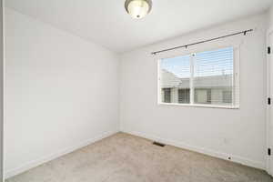 Spare room featuring baseboards and light colored carpet