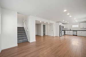 Unfurnished living room with stairway, light wood finished floors, and recessed lighting