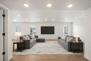 Living room featuring light wood-style flooring and healthy amount of natural light. Virtually staged.