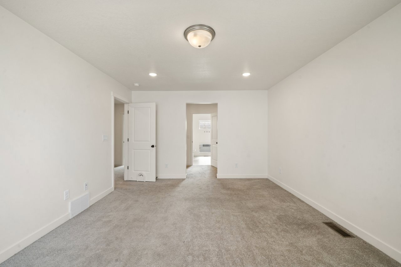 Empty room with light colored carpet and recessed lighting