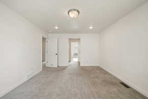 Empty room with light colored carpet and recessed lighting