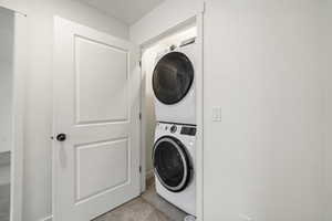 Washroom featuring stacked washing machine and dryer and carpet floors