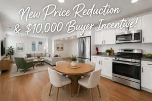 Open-concept living space featuring wood-finish flooring, a contemporary kitchen with stainless steel appliances, white cabinetry, and a dining area with a round table
