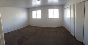 Unfurnished bedroom with two closets and dark carpet