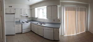 Kitchen with white appliances, white cabinets, light tile patterned floors, and light countertops