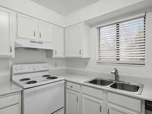 Kitchen with electric stove, white cabinetry, under cabinet range hood, a textured ceiling, and dishwasher