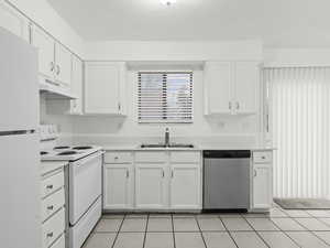 Kitchen with white appliances, white cabinets, light tile patterned floors, a textured ceiling, and light countertops