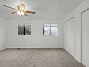 Bedroom with light carpet, a textured ceiling, and ceiling fan