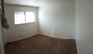 Unfurnished room featuring dark carpet and baseboards