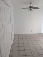 Tiled empty room with a ceiling fan and baseboards