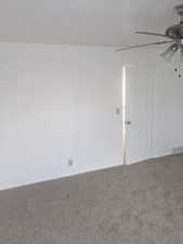 Carpeted spare room featuring ceiling fan and baseboards