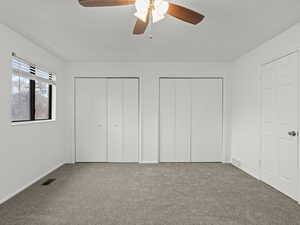 Main bedroom with two closets, carpet floors, and ceiling fan