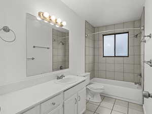 Full bath featuring vanity, shower / tub combination, light tile patterned floors, and a textured wall