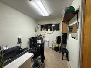 Office featuring a textured wall, a textured ceiling, and light floors