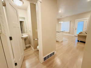 Corridor featuring light wood-style floors, a textured ceiling, and a chandelier